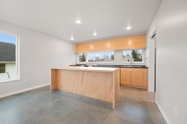 kitchen featuring light brown cabinetry, a center island, concrete flooring, and sink