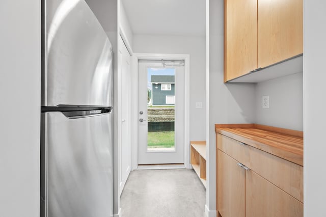 kitchen with stainless steel fridge, light brown cabinetry, and a healthy amount of sunlight