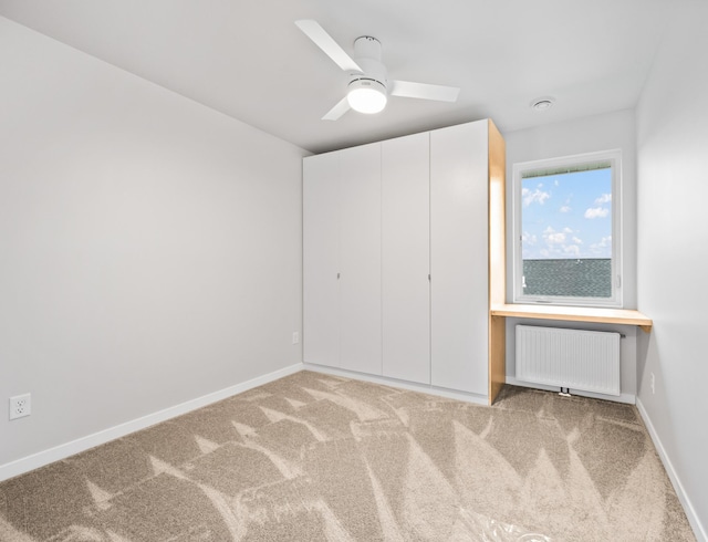 unfurnished bedroom with carpet flooring, a closet, ceiling fan, and radiator heating unit