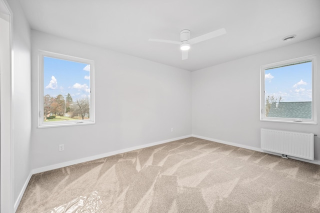 spare room featuring radiator, ceiling fan, and carpet