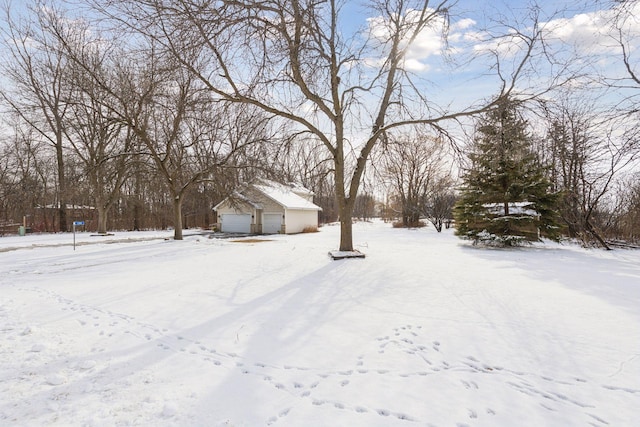 snowy yard with a detached garage and an outdoor structure