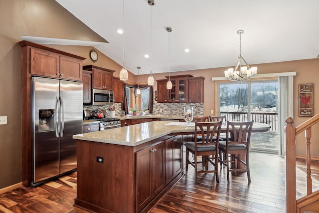 kitchen with a wealth of natural light, stainless steel appliances, a center island, and vaulted ceiling