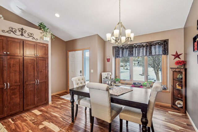 dining room with a chandelier, wood finished floors, baseboards, and vaulted ceiling