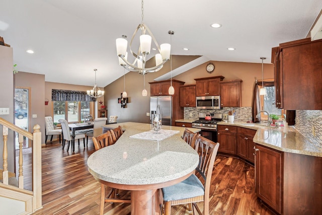 kitchen featuring dark wood-style floors, a sink, stainless steel appliances, vaulted ceiling, and a notable chandelier