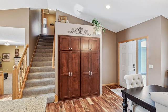 foyer featuring lofted ceiling, stairway, baseboards, and light wood-type flooring