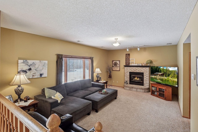 living room featuring visible vents, a textured ceiling, carpet, rail lighting, and a fireplace