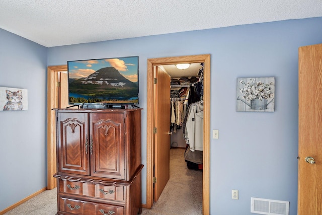 hall featuring visible vents, baseboards, a textured ceiling, and carpet flooring