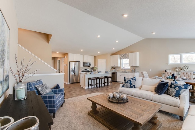 living room with light wood finished floors, vaulted ceiling, and recessed lighting