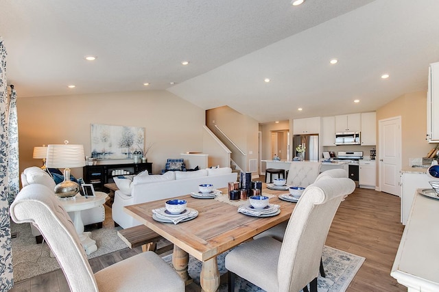 dining space with vaulted ceiling and light hardwood / wood-style flooring