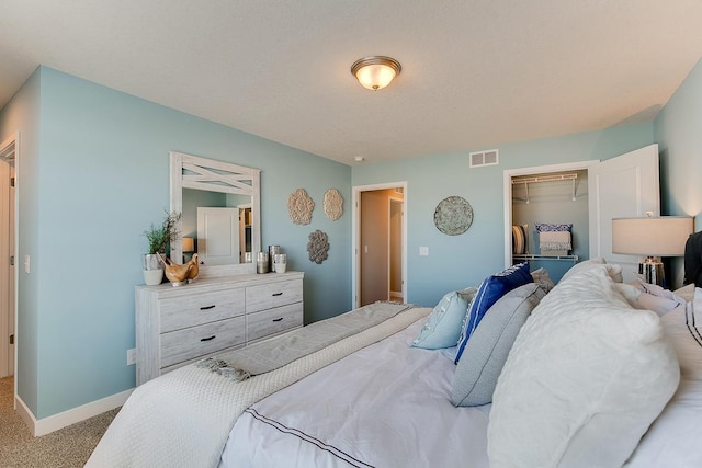 carpeted bedroom featuring baseboards, visible vents, a walk in closet, and a closet