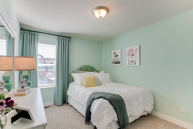 bedroom featuring visible vents, light colored carpet, a textured ceiling, and baseboards