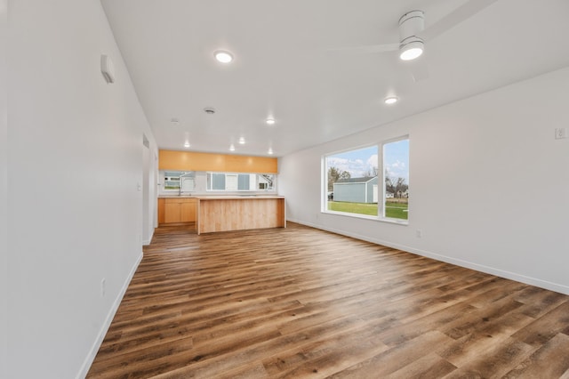 unfurnished living room featuring ceiling fan and dark hardwood / wood-style flooring