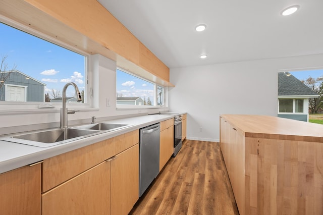 kitchen featuring appliances with stainless steel finishes, sink, light brown cabinets, light hardwood / wood-style flooring, and a center island