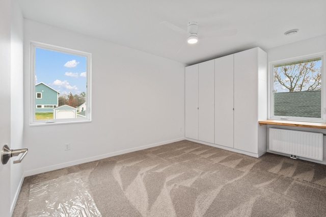 712 8th Ave, Grand Rapids, MN 55744 - unfurnished bedroom with radiator, carpet, and a ceiling fan