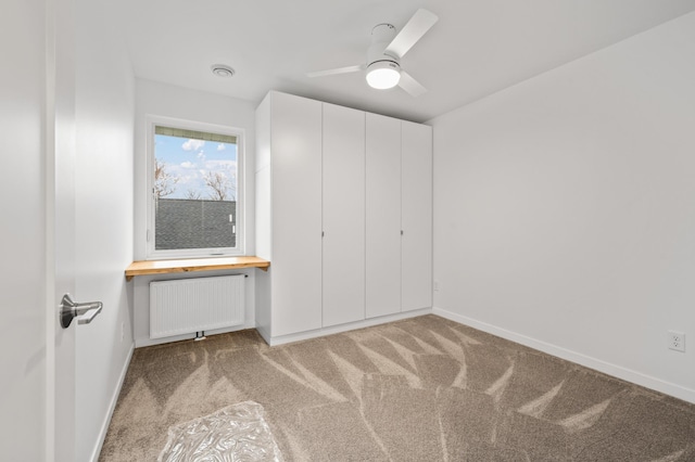 unfurnished bedroom featuring ceiling fan, light carpet, radiator, and a closet