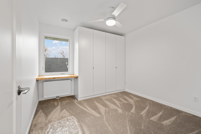 712 8th Ave, Grand Rapids, MN 55744 - unfurnished bedroom featuring radiator heating unit, built in desk, light carpet, and a ceiling fan