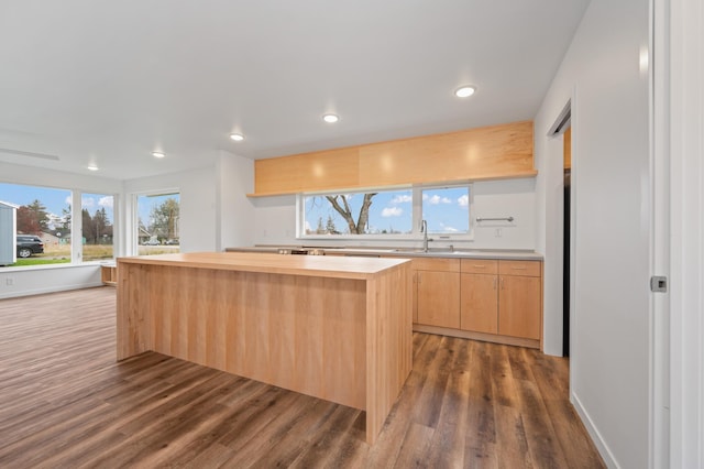 kitchen with sink, dark hardwood / wood-style floors, light brown cabinetry, a kitchen island, and butcher block counters