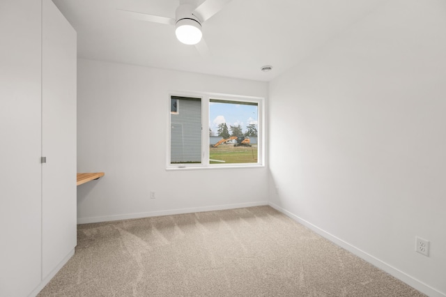 carpeted spare room with ceiling fan