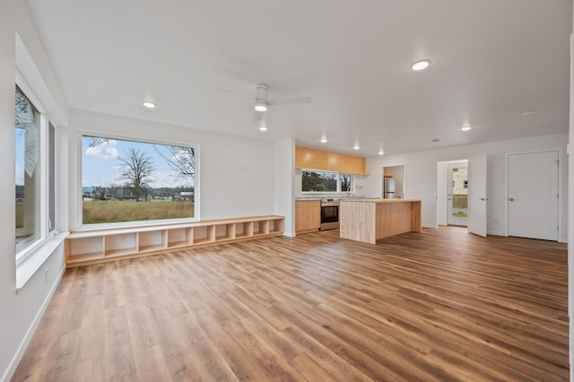 unfurnished living room with ceiling fan, a healthy amount of sunlight, and light hardwood / wood-style flooring