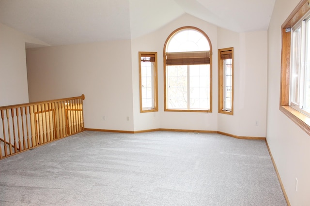 unfurnished room with plenty of natural light, lofted ceiling, and light carpet