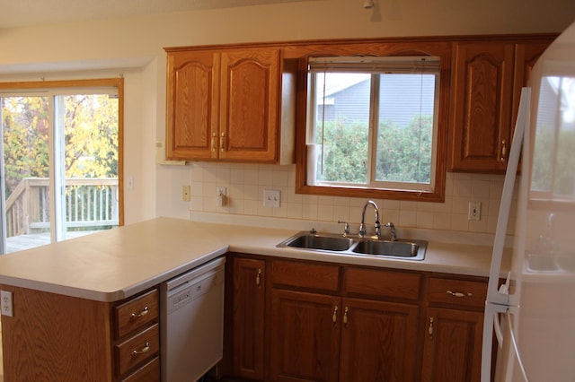 kitchen with kitchen peninsula, white appliances, a wealth of natural light, and sink