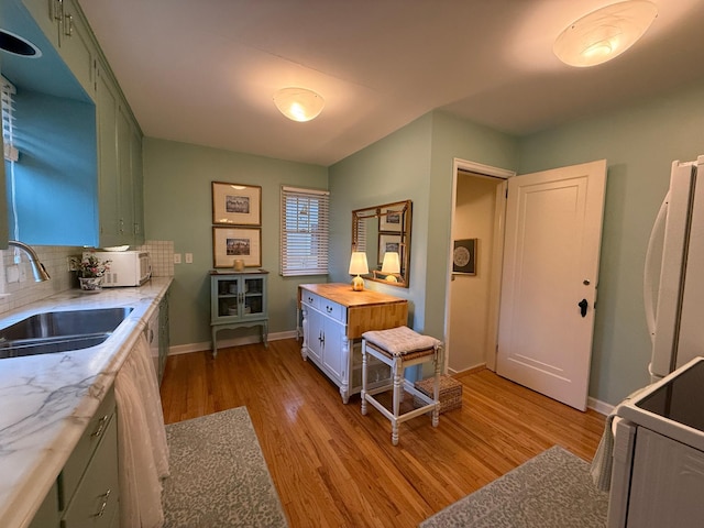 kitchen featuring sink, white appliances, green cabinets, wood counters, and light wood-type flooring