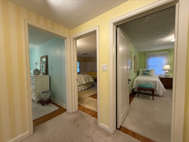 corridor with light carpet and a textured ceiling