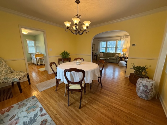 dining room with crown molding, wood-type flooring, and a chandelier