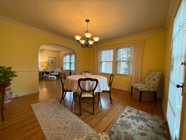 dining room with wood-type flooring, ornamental molding, and an inviting chandelier