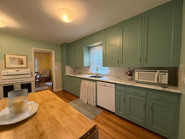 kitchen with sink, white appliances, light hardwood / wood-style floors, green cabinetry, and decorative backsplash