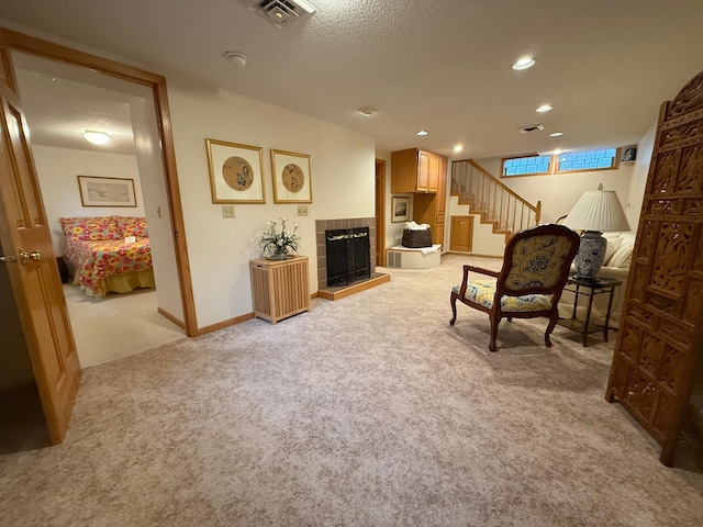 sitting room featuring light carpet, a tile fireplace, and a textured ceiling