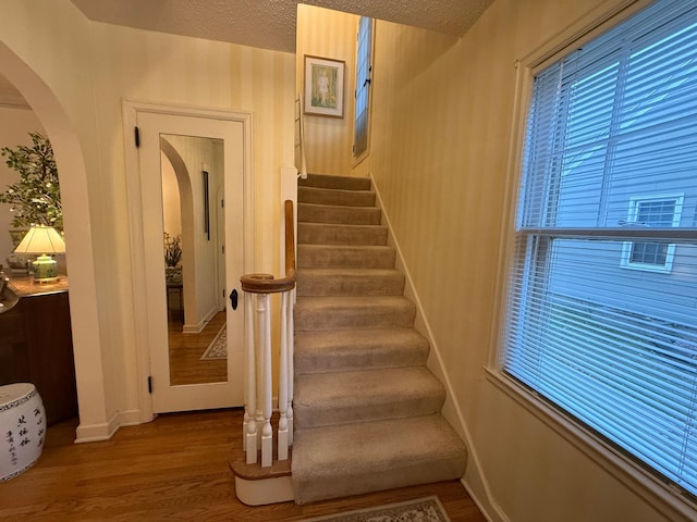 stairs featuring wood-type flooring and a textured ceiling