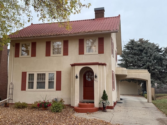 mediterranean / spanish home featuring driveway, stucco siding, a chimney, and an attached garage