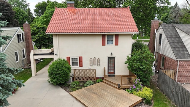 607 Lake Ave, Worthington, MN 56187 - view of front of property with stucco siding, a tile roof, a deck, and a chimney