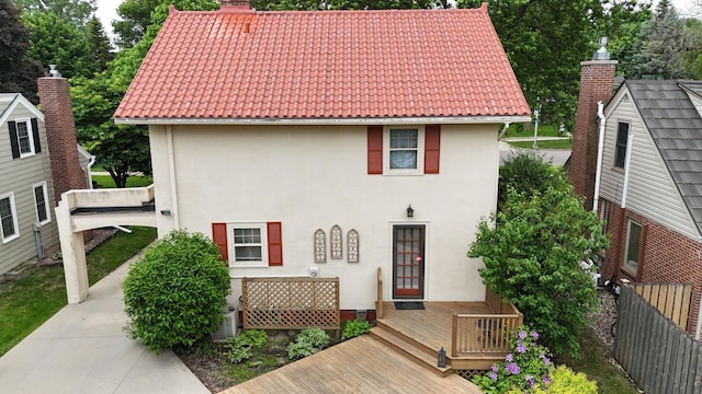 607 Lake Ave, Worthington, MN 56187 - view of front of house featuring a tiled roof, a chimney, stucco siding, and a deck