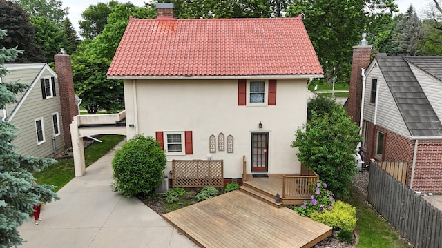 607 Lake Ave, Worthington, MN 56187 - back of property with stucco siding, a tile roof, a chimney, and a deck