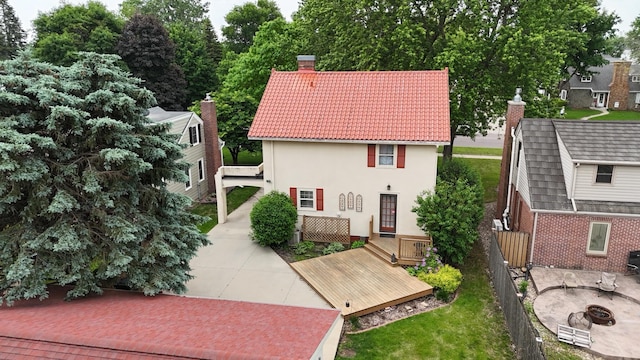 607 Lake Ave, Worthington, MN 56187 - rear view of house with an outdoor fire pit, a chimney, a deck, a tiled roof, and stucco siding