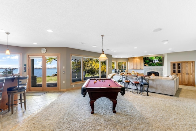 rec room with pool table, a water view, and a textured ceiling