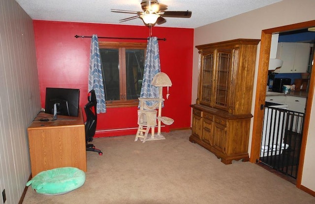 carpeted office space with a textured ceiling and ceiling fan