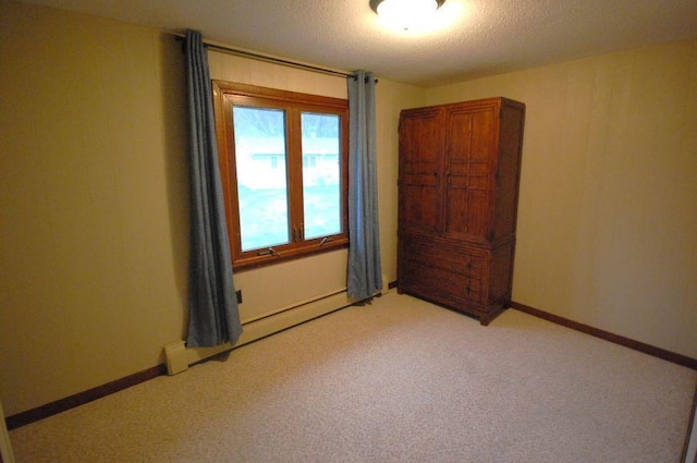 spare room with a baseboard radiator, a textured ceiling, and light colored carpet