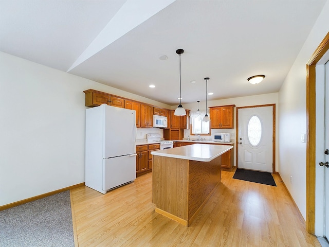 kitchen with white appliances, sink, light hardwood / wood-style floors, a kitchen island, and hanging light fixtures