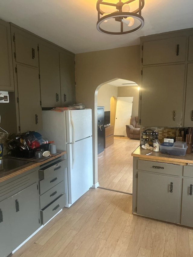 kitchen featuring white refrigerator, light wood-type flooring, and a chandelier