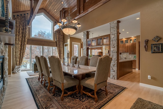 5441 Raven Point Rd, Spring Lake Twp, MN 55372 - dining room with high vaulted ceiling, ornate columns, light wood-style floors, wood ceiling with exposed beams, and a fireplace