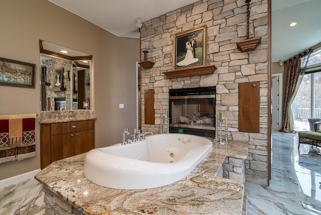 5441 Raven Point Rd, Spring Lake Twp, MN 55372 - bathroom featuring vanity, a tub with jets, marble tiled floors, a fireplace, and baseboards