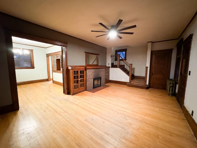 living room with ceiling fan with notable chandelier, light hardwood / wood-style floors, and a fireplace