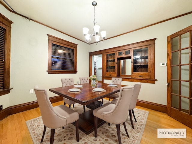 dining room with ornamental molding, light hardwood / wood-style floors, and a notable chandelier