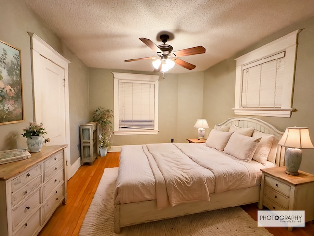 bedroom with ceiling fan, a textured ceiling, and light wood-type flooring