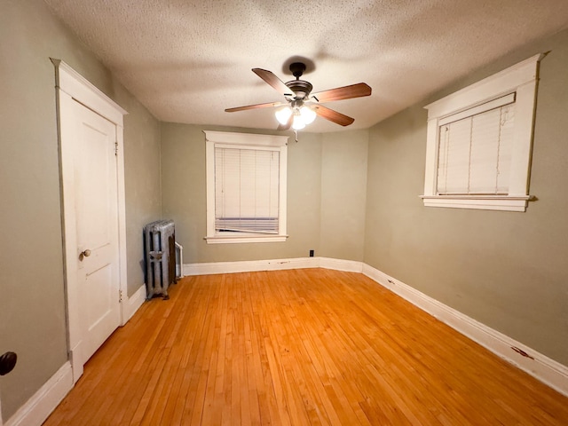 spare room featuring light hardwood / wood-style floors, a textured ceiling, ceiling fan, and radiator