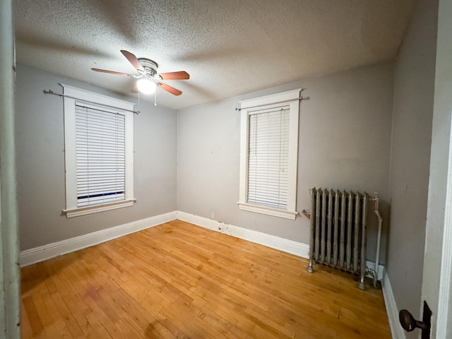 unfurnished room with hardwood / wood-style flooring, ceiling fan, a textured ceiling, and radiator heating unit