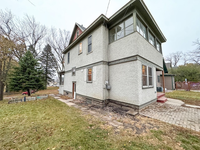 view of side of home with central AC unit, a patio area, and a lawn